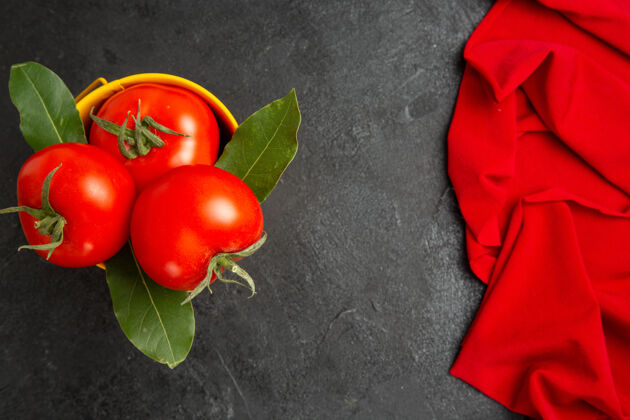 磨碎顶视图一桶西红柿和月桂叶和红毛巾在黑暗的地面上健康食品毛巾