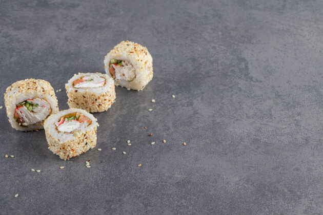 美食寿司卷装饰芝麻在石头背景上新鲜筷子寿司