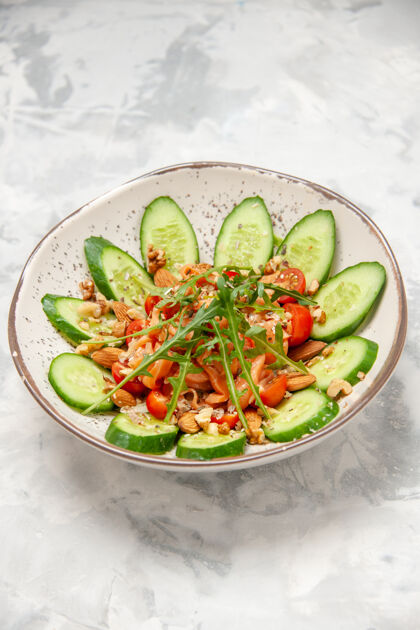 健康自制健康美味素食沙拉的垂直视图 用切碎的黄瓜装饰在一个碗里 表面是白色的午餐晚餐碗