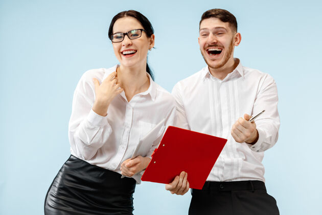 微笑商业伙伴关系的概念年轻快乐微笑的男女站在工作室蓝色背景下会议英俊八卦