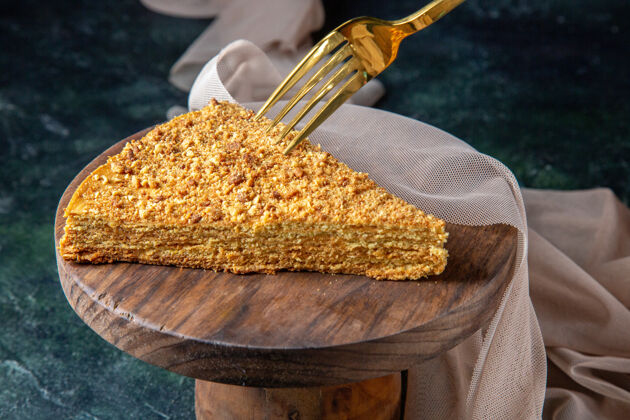 切片正面是美味的蜂蜜蛋糕片 它放在圆木板深色的表面上面包谷类甜点