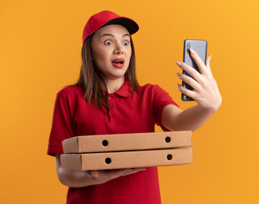 电话穿着制服的焦急漂亮的女送货员拿着披萨盒 看着橙色的电话盒子漂亮橘子