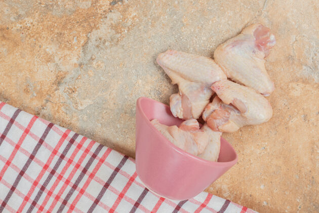 粉色未经料理的鸡腿放在大理石表面的粉红色盘子里大理石美味肉