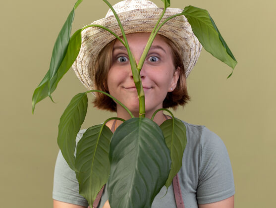 年轻令人印象深刻的年轻斯拉夫女园丁戴着园艺帽举行橄榄绿植物花园橄榄斯拉夫
