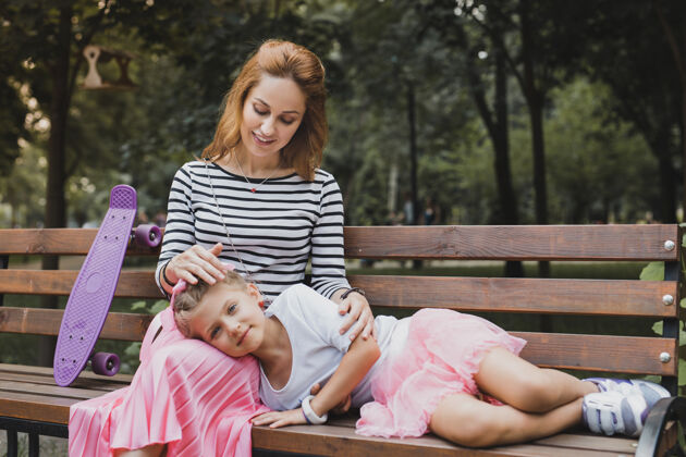 情绪疲惫的女儿在公园里走了很长时间后 疲惫可爱的女儿躺在妈妈的膝盖上生态积极环境
