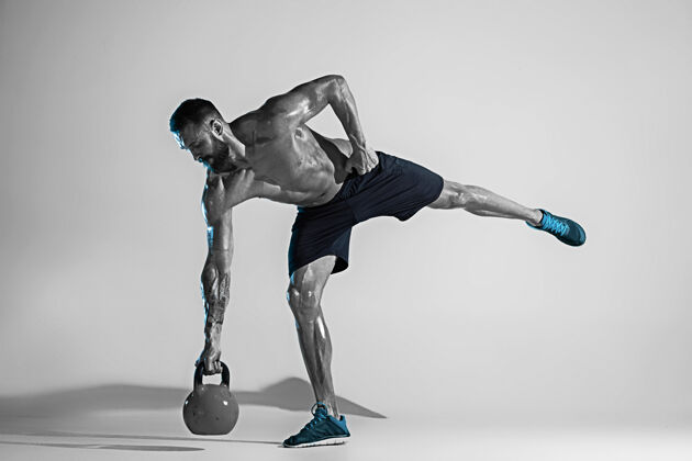 运动像一块石头年轻的白人健美运动员在霓虹灯下的工作室背景下训练肌肉发达的男模体重运动的概念 健美 健康的生活方式 运动和动作训练力量努力