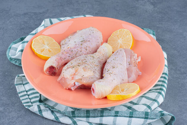 鸡肉生鸡腿和柠檬放在橙色盘子里餐生的烹饪