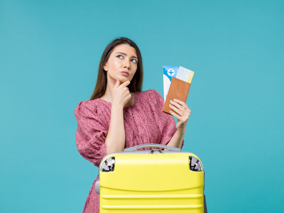 蓝色前景度假中的女性拿着她的钱包和机票在蓝色背景上旅行度假的女性夏日海上女人假期举行