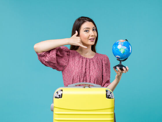 呼叫前景度假中的女性手持蓝色背景上的小地球仪出海旅行的女性度假暑假举行女人度假
