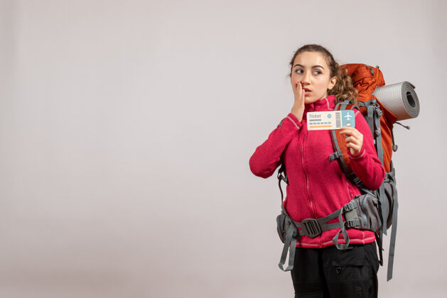 旅行困惑的年轻旅行者的正面图 背着大背包 举着免费的旅行票快乐抱人