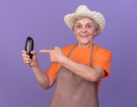 老人印象深刻的上了年纪的女园丁戴着园艺帽拿着紫色的茄子指着指点印象帽子