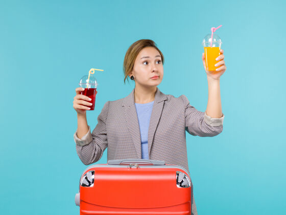 成人前视图：度假中的女性手持新鲜饮料乘坐蓝色背景的旅行度假海上飞机旅行女人观点