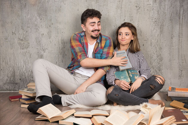 情侣一对漂亮的夫妇坐在地板上 手里拿着很多书坐着女士模特