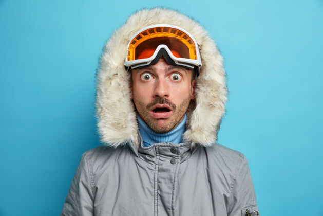 运动尴尬活跃的男人喜欢冬季运动 穿着暖和的外套 表情震惊地盯着他看冬季人休息
