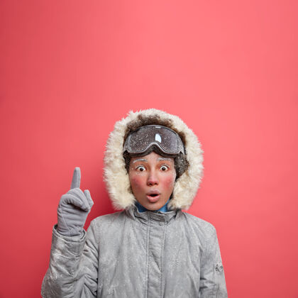 极端寒假概念震惊的冻僵的年轻女子张大嘴巴 点以上震惊极低的温度和大雪去滑雪在十二月穿着外套活动凝视寒冷