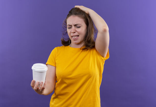 恼怒恼怒的年轻休闲女子手持塑料咖啡杯 手放在头上孤立的紫色空间随意女人持有