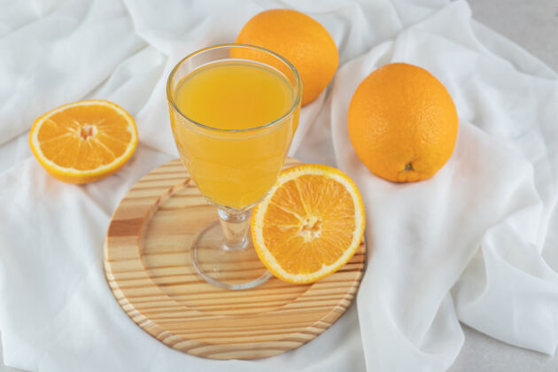 正餐一杯果汁和新鲜的橙子放在木盘上美味鸡尾酒果汁