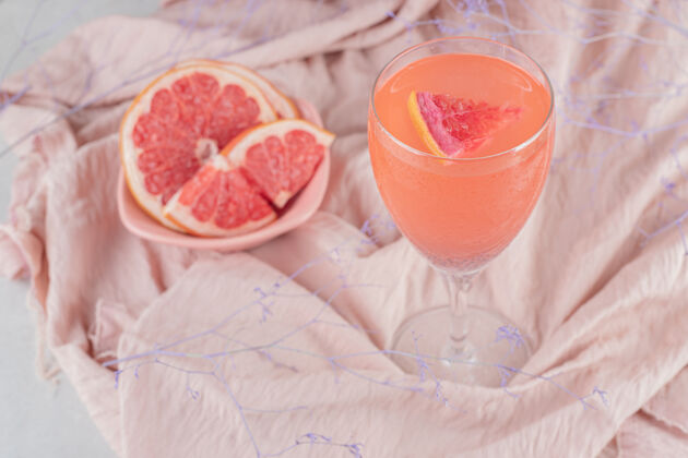 新鲜一杯果汁和新鲜的葡萄柚在粉红色的布上营养葡萄柚膳食