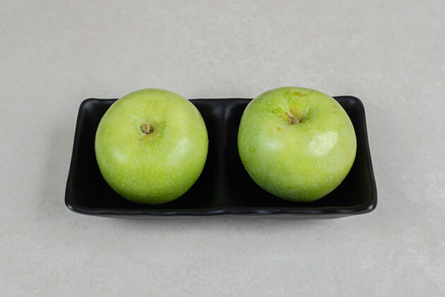 生的新鲜的青苹果放在黑盘子里一餐新鲜配料