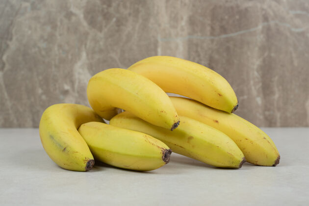 成熟灰色桌子上放着一堆黄色的香蕉营养有机配料