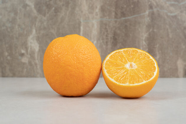 有机新鲜的整片和半片橙子放在灰色的桌子上酸营养自然