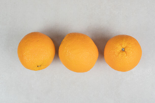 有机三个完整的橘子在灰色的表面异国情调食物配料