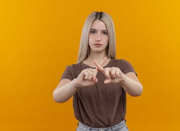 金发严肃的年轻金发女孩在孤立的橙色空间和复制空间上做着“不”的手势手势橙色女孩