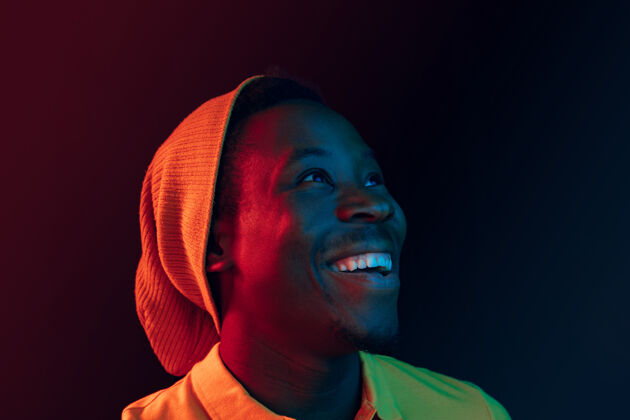 情绪在黑色霓虹灯工作室背景下 一个快乐的非洲裔美国年轻人微笑的特写肖像孤独迪斯科微笑