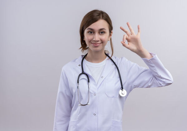 医生很高兴年轻的女医生穿着医用长袍和听诊器做了可以的标志和复印空间女性标志复制