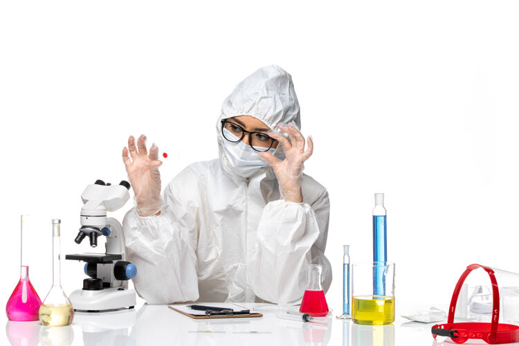 病毒前视图穿着特殊防护服的女化学家正在检查白色背景病毒化学covid大流行的样本化学专业套装