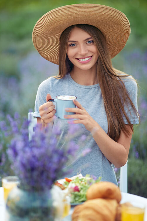 蜂蜜时尚女人在薰衣草地里享受咖啡羊角面包女孩花束
