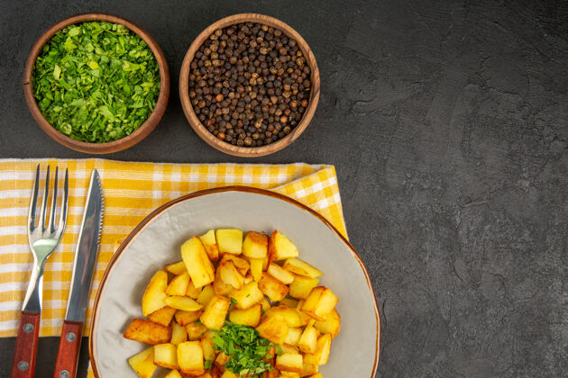 食物美味的油炸土豆在深灰色的表面与绿色盘子顶视图豆类黑色美味