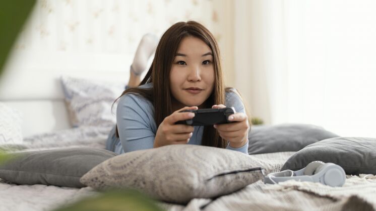 娱乐在床上玩电子游戏的女孩爱好女孩乐趣