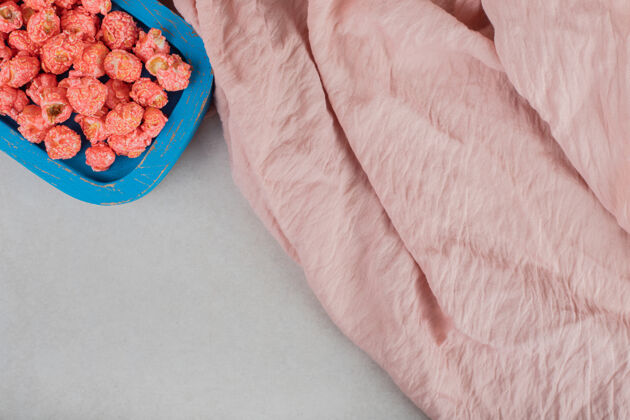 爆米花粉色桌布旁边放着一小盘爆米花糖放在大理石桌上糖果仁顶视图