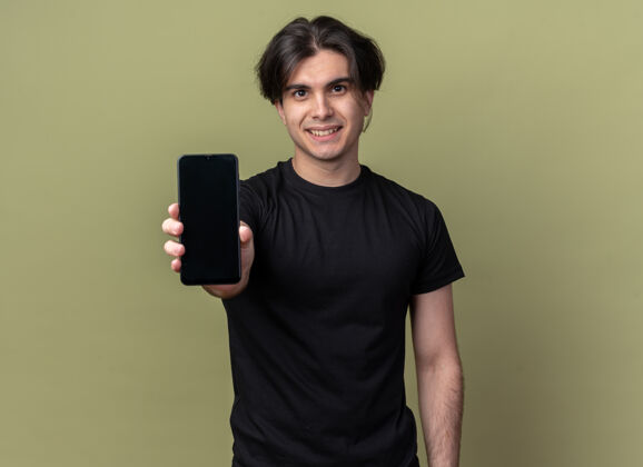 抱着一个穿着黑色t恤的年轻帅哥在橄榄绿的墙前把电话拿了出来感觉人男人