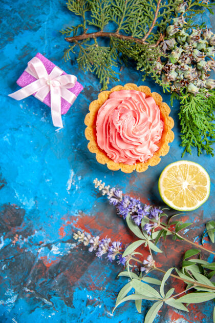 奶油小馅饼的俯视图与粉红色糕点奶油柠檬片树枝上的蓝色表面柠檬花插花