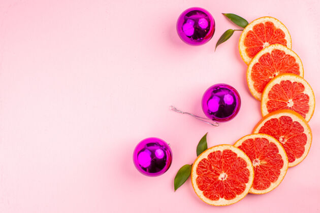 艺术粉红色表面上美味的葡萄柚和多汁的水果片的俯视图花卉装饰品水果