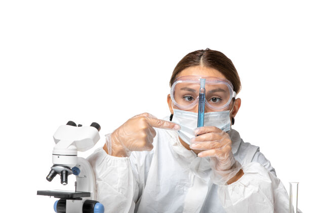 防护正面图：女医生穿着防护服 戴着口罩 拿着装有蓝色溶液的烧瓶 背景是浅白色的冠状病毒大流行病毒专业病毒白色
