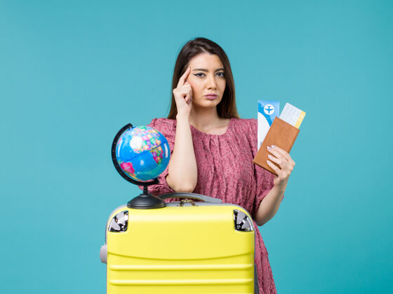 微笑前视图女性在旅行中拿着钱包和机票蓝色背景海上旅行女性旅行度假之旅航程票女人