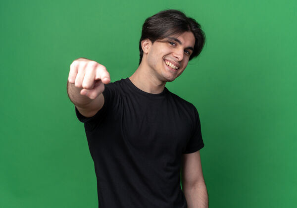 表情微笑的年轻帅哥穿着黑色t恤 在绿色的墙上展示你的孤立姿态穿着站着手势