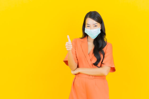 疾病肖像美丽的亚洲年轻女子戴着黄色的口罩保护自己流行病毒大流行