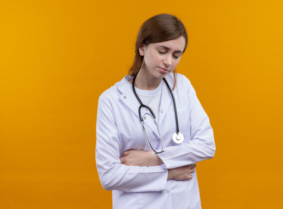 医生疼痛的年轻女医生穿着医用长袍和听诊器把手放在肚子上闭着眼睛在孤立的橙色空间与复制空间橙色女性手