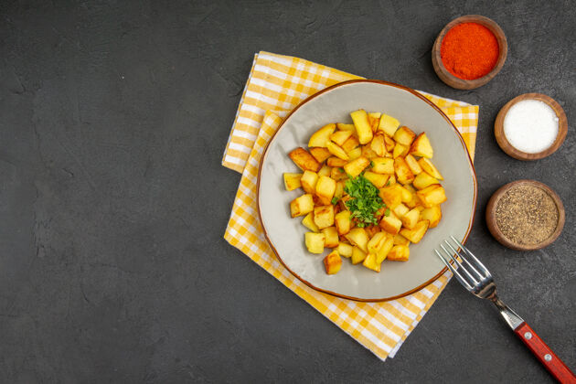 晚餐美味的炸土豆顶视图在深灰色的表面与调味品盘子里水果调味品盘子