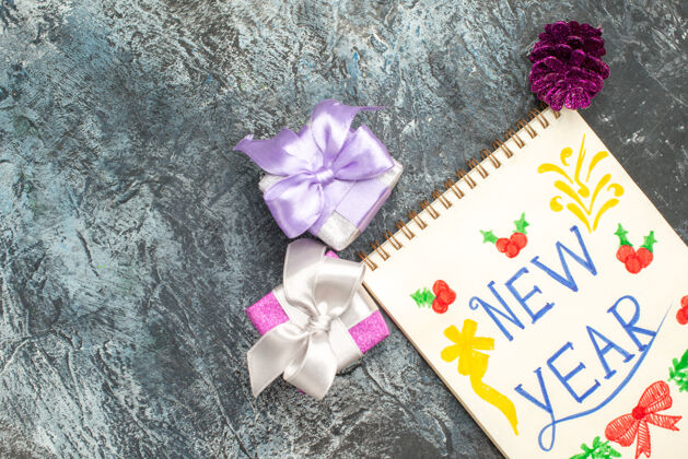 丝带用铅笔和小礼物在灰色表面的新年笔记俯视图文案圣诞节蝴蝶结