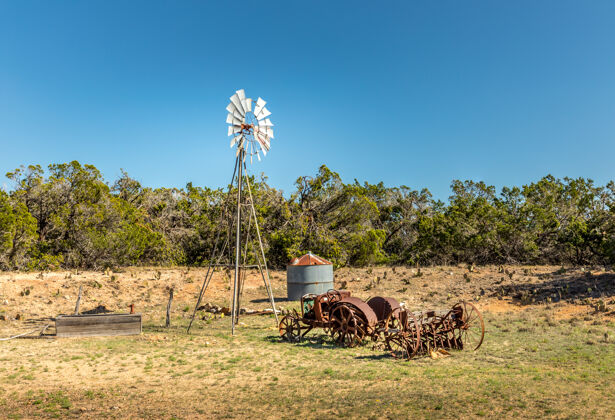 天空得克萨斯偏僻道路上生锈的旧拖拉机和风车乡村生锈德克萨斯