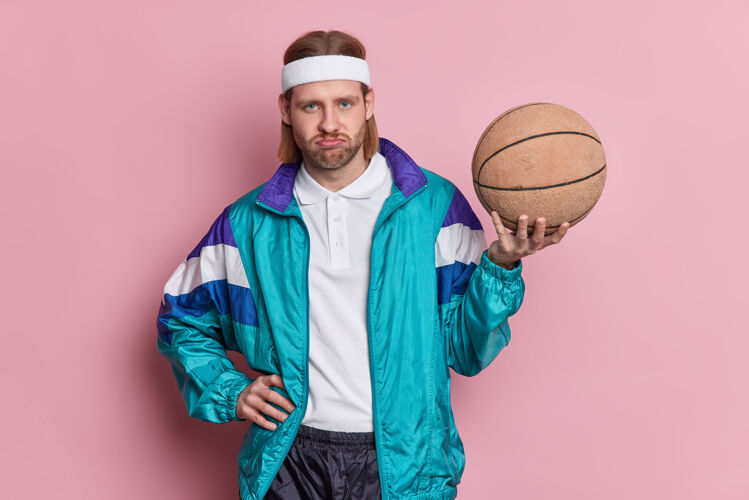 粉色不高兴的男子篮球运动员拿着球不高兴地看着镜头运动运动装球员