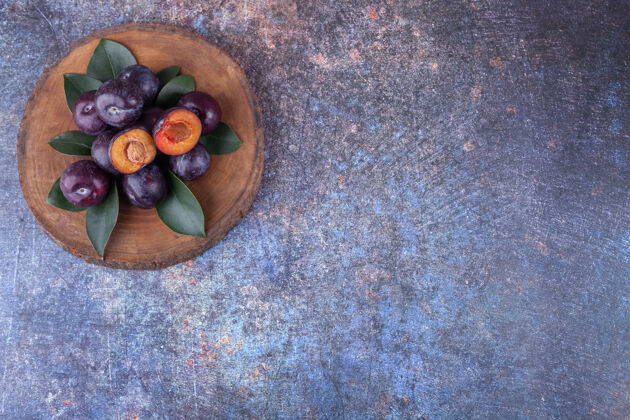 天然一束新鲜的紫色李子放在木片上成熟种子李子