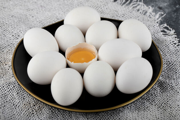 有机白鸡蛋和蛋黄放在黑盘子里烹饪母鸡家禽