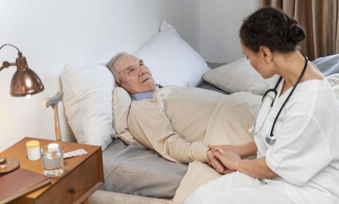 老年年轻的医生正在和她的老病人谈话内部老年人室内