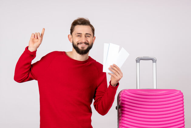 机票正面图：年轻男性 带着粉色包 手持白墙旅游度假航班暑期旅游机票成年人游客肖像